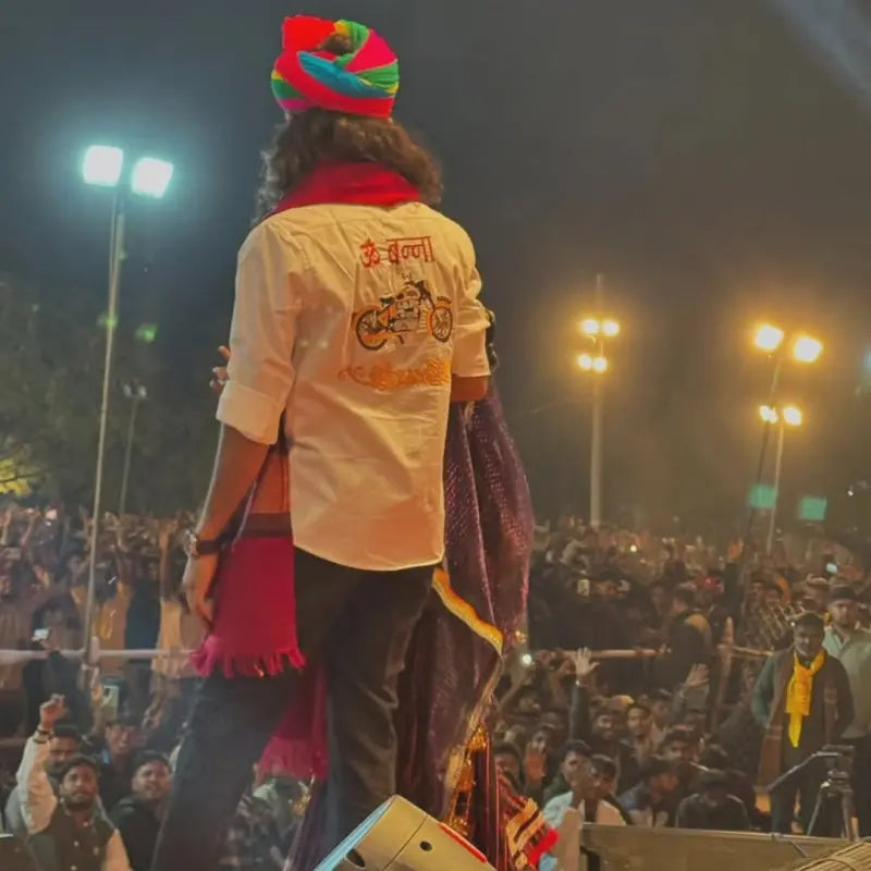 Modern Marwar Om Banna logo shirt worn by a man at an outdoor event with a large crowd